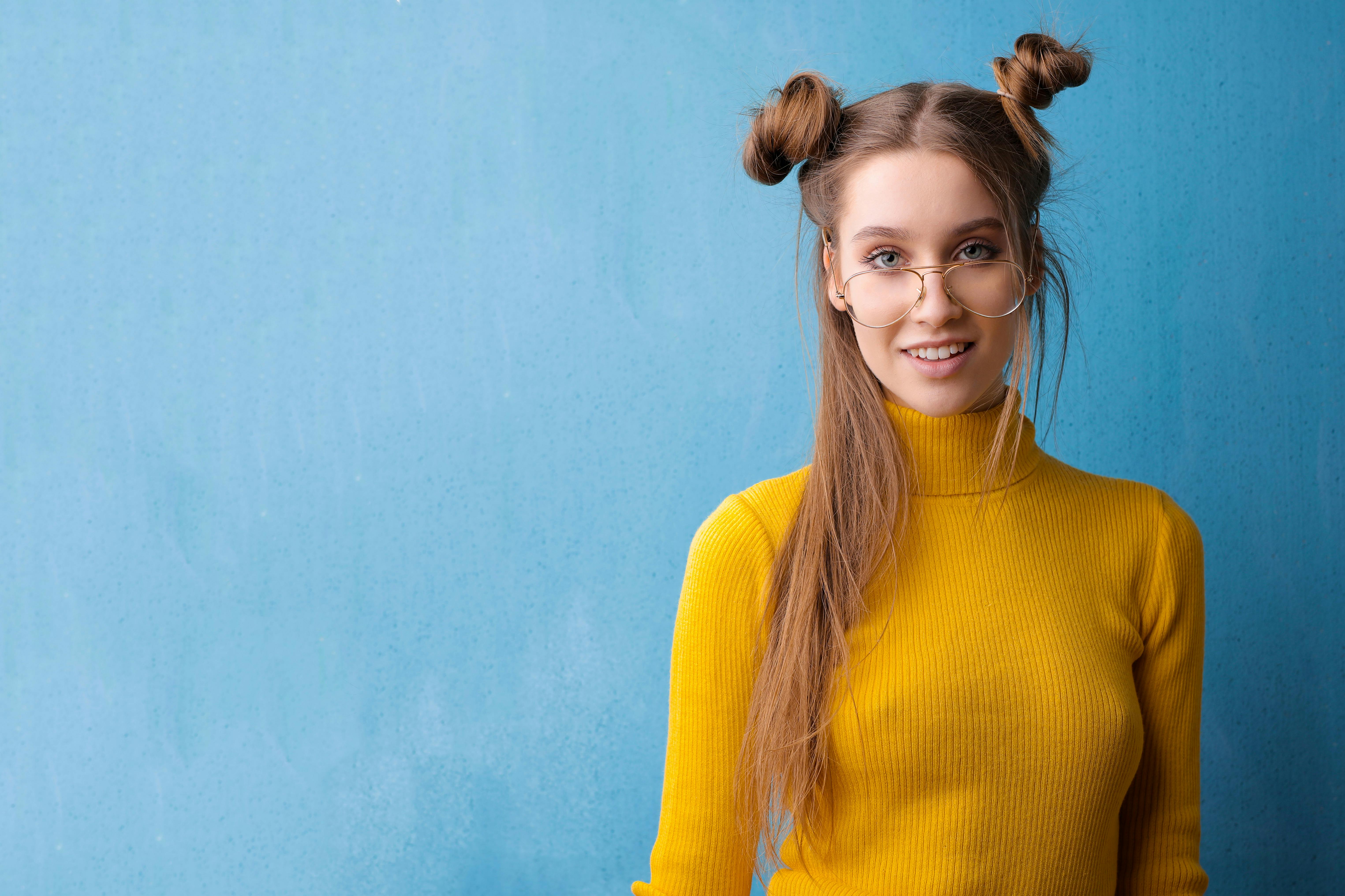 一位戴眼镜的迷人年轻女子在亮蓝色背景下微笑