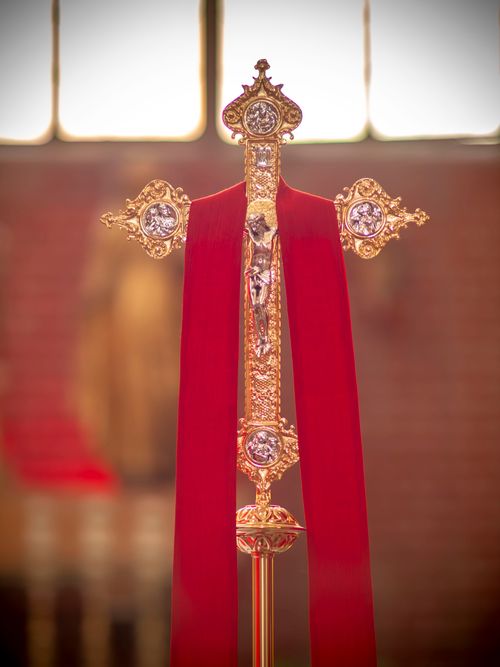 Free A detailed gold cross adorned with red fabric, symbolizing faith and devotion in a church setting. Stock Photo