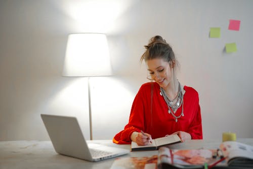 Free Woman in Red Long Sleeve Shirt Sitting Near Table Stock Photo