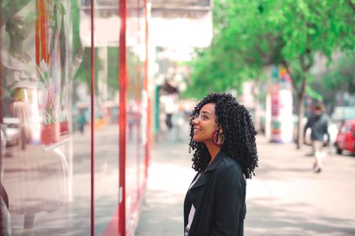 Free Happy woman in a city enjoying window shopping on a sunny day. Stock Photo