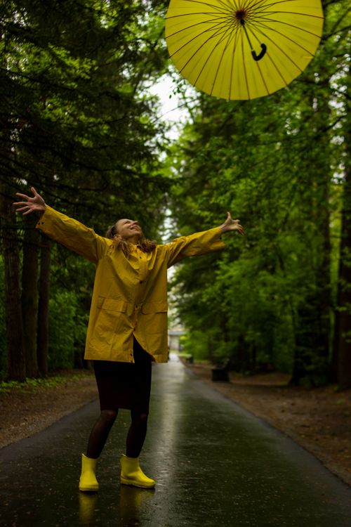 A Woman in Yellow Raincoat Standing on Steps · Free Stock Photo