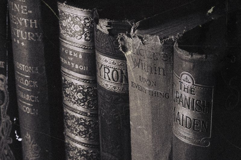 Close-up of vintage hardcover books with decorative spines in grayscale.