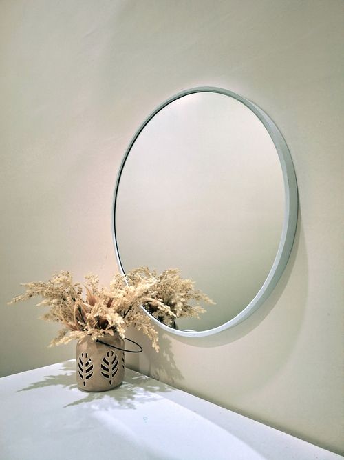 Free Aesthetic minimalist interior featuring a round mirror and decorative vase on a white surface. Stock Photo