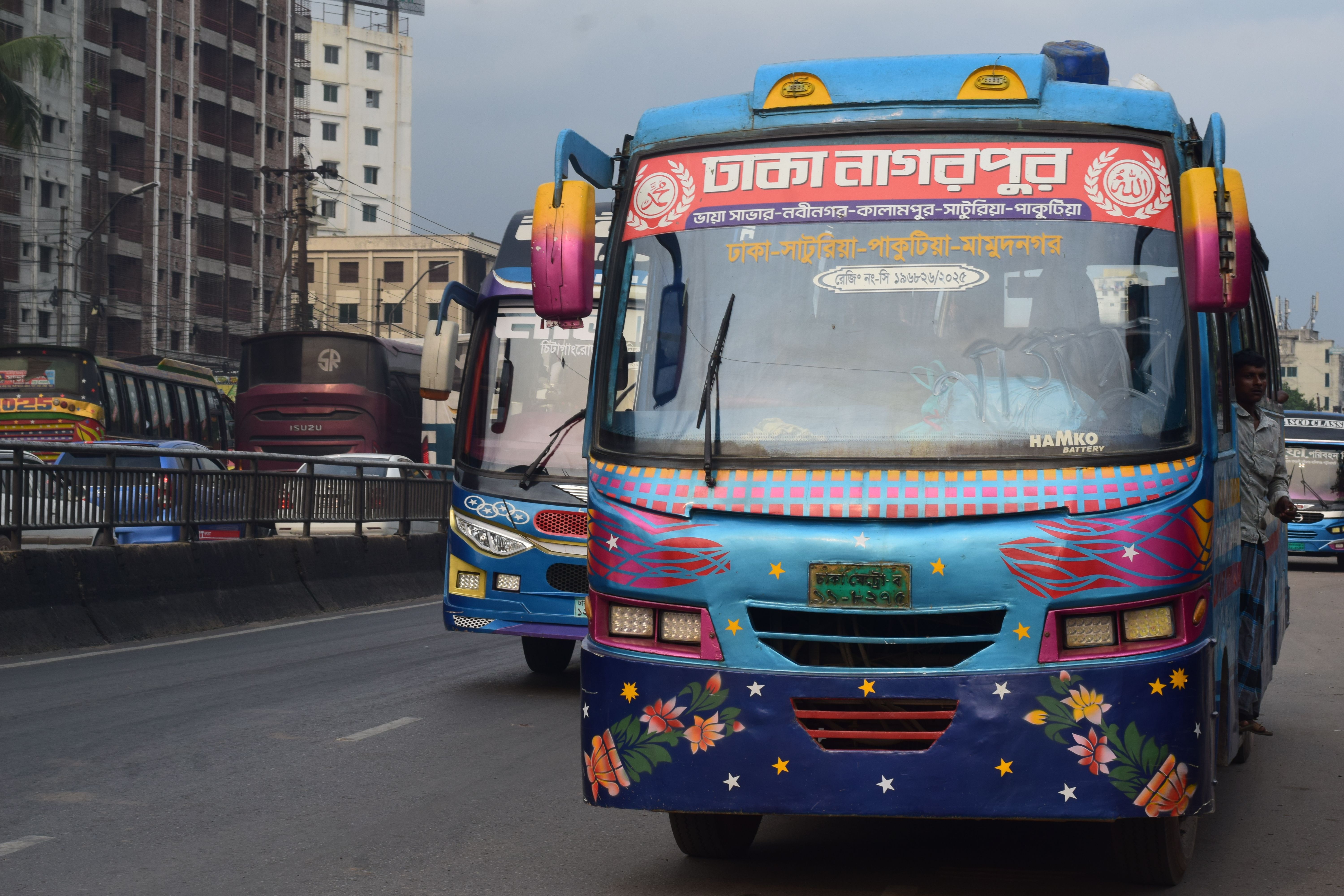 Vibrant decorated buses on a busy street in Dhaka, Bangladesh, showcasing local culture and urban transport.
