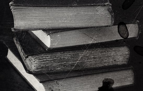 Close-up of a stack of vintage books in black and white, showcasing the texture of old paper.