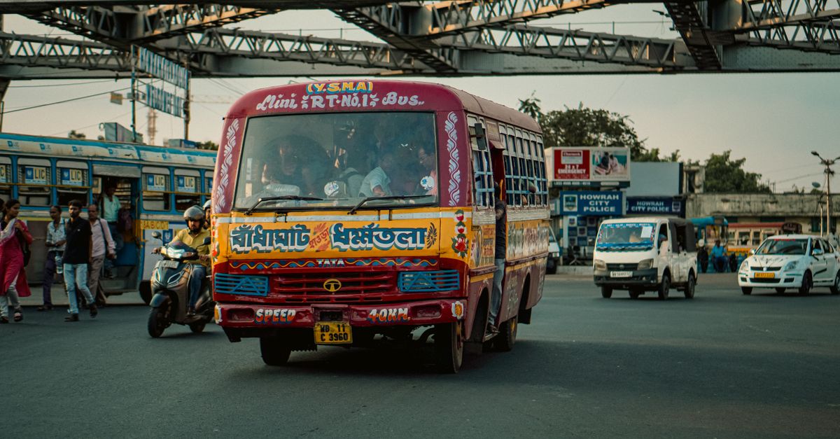 Vibrant city scene in Kolkata, India with colorful bus, vehicles, and commuters.