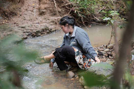 A woman embraces nature by a serene riverbank in Aceh, Indonesia, capturing a moment of tranquility.