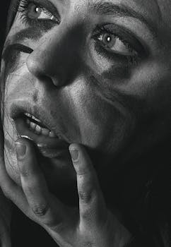 一幅强烈的黑白肖像展现了一个女人沉思的姿态，妆容已花