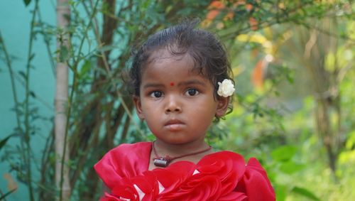 Free A young girl in a red dress stands outdoors, beautifully capturing innocence and cultural richness. Stock Photo