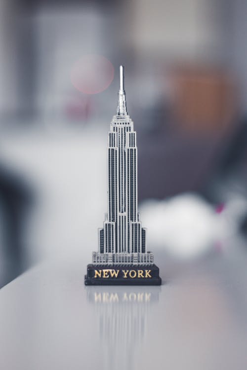 Small metal souvenir in shape of Empire State Building with New York inscription placed on white table