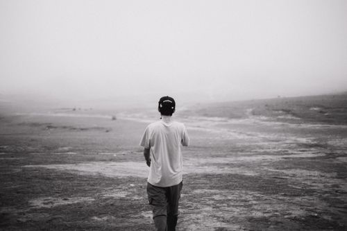 Free A lone figure walks in a vast, misty landscape, captured in moody black and white tones. Stock Photo