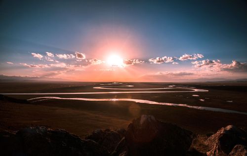 Free Stunning view of a sunrise over a winding river in a vast grassland landscape. Stock Photo