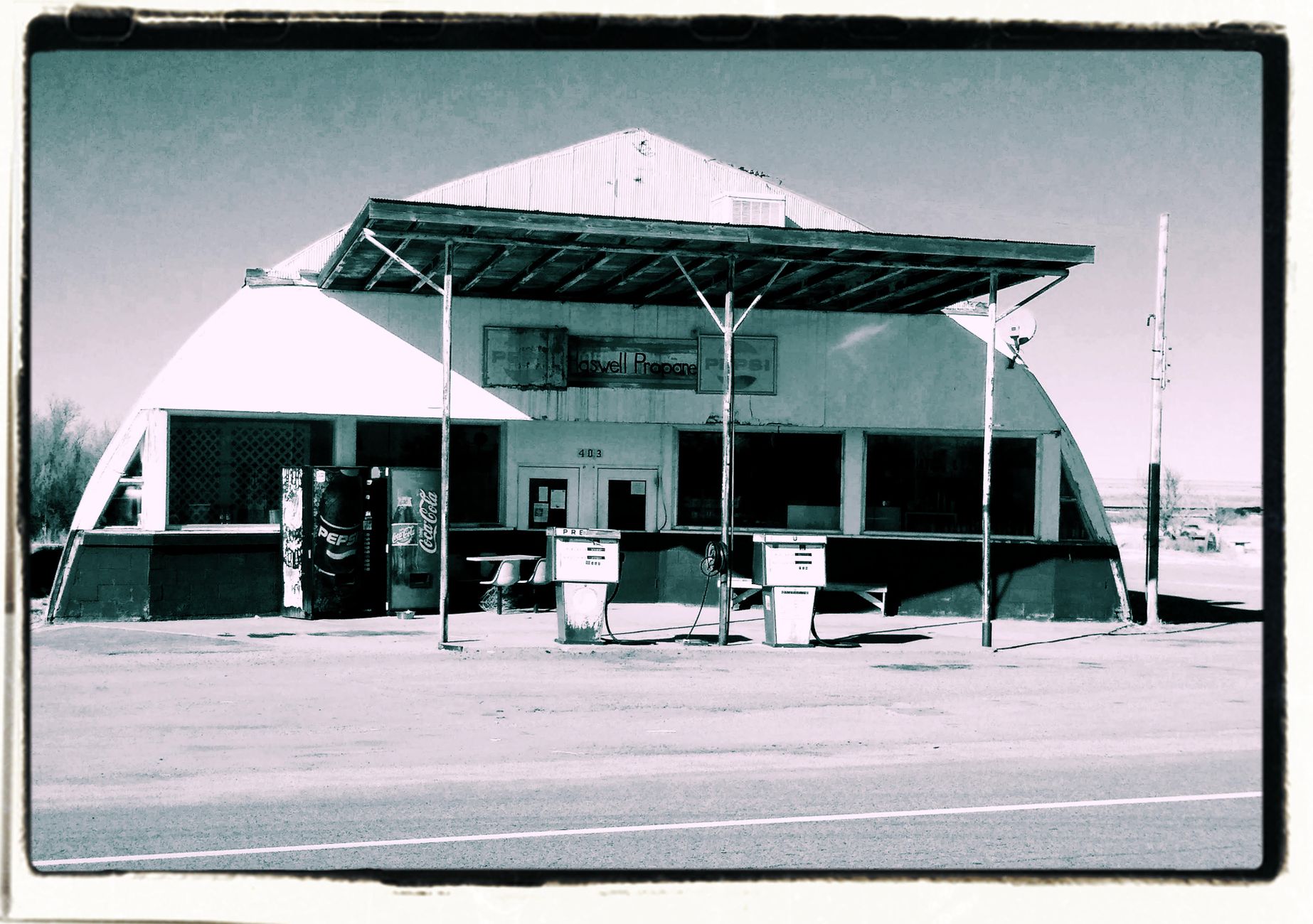 A 1973 gas station in New York with long queues, vintage cars, and handwritten fuel rationing signs
