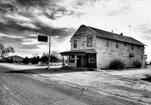 黑白照片里，一栋废弃的木屋矗立在贫瘠的乡村景观中