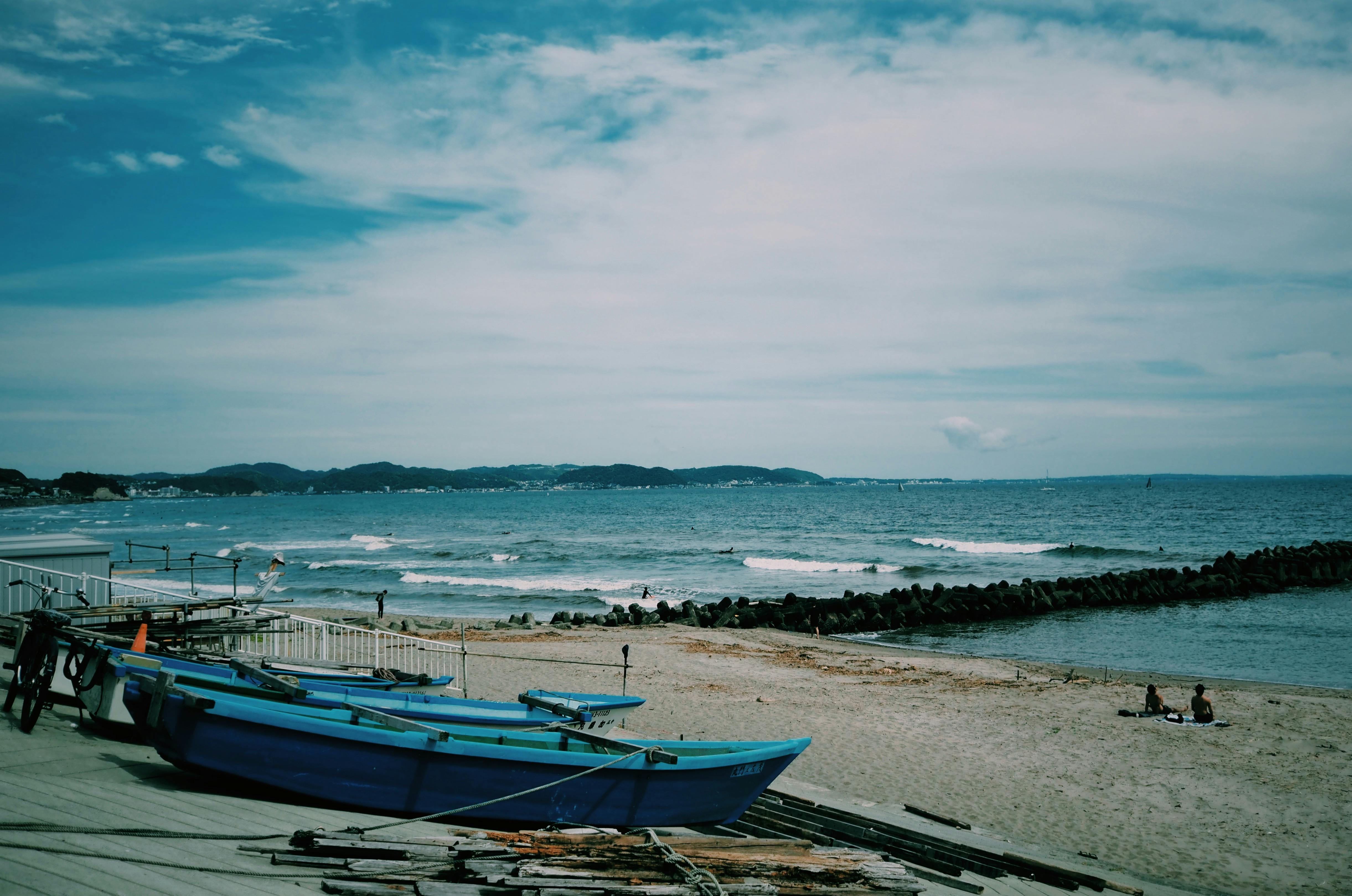 Tranquil beach setting in Tokyo, Japan with boats and a distant coastline under a vibrant sky.