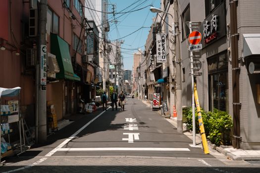 A quiet street in Tokyo, showcasing urban life and traditional architecture on a sunny day.