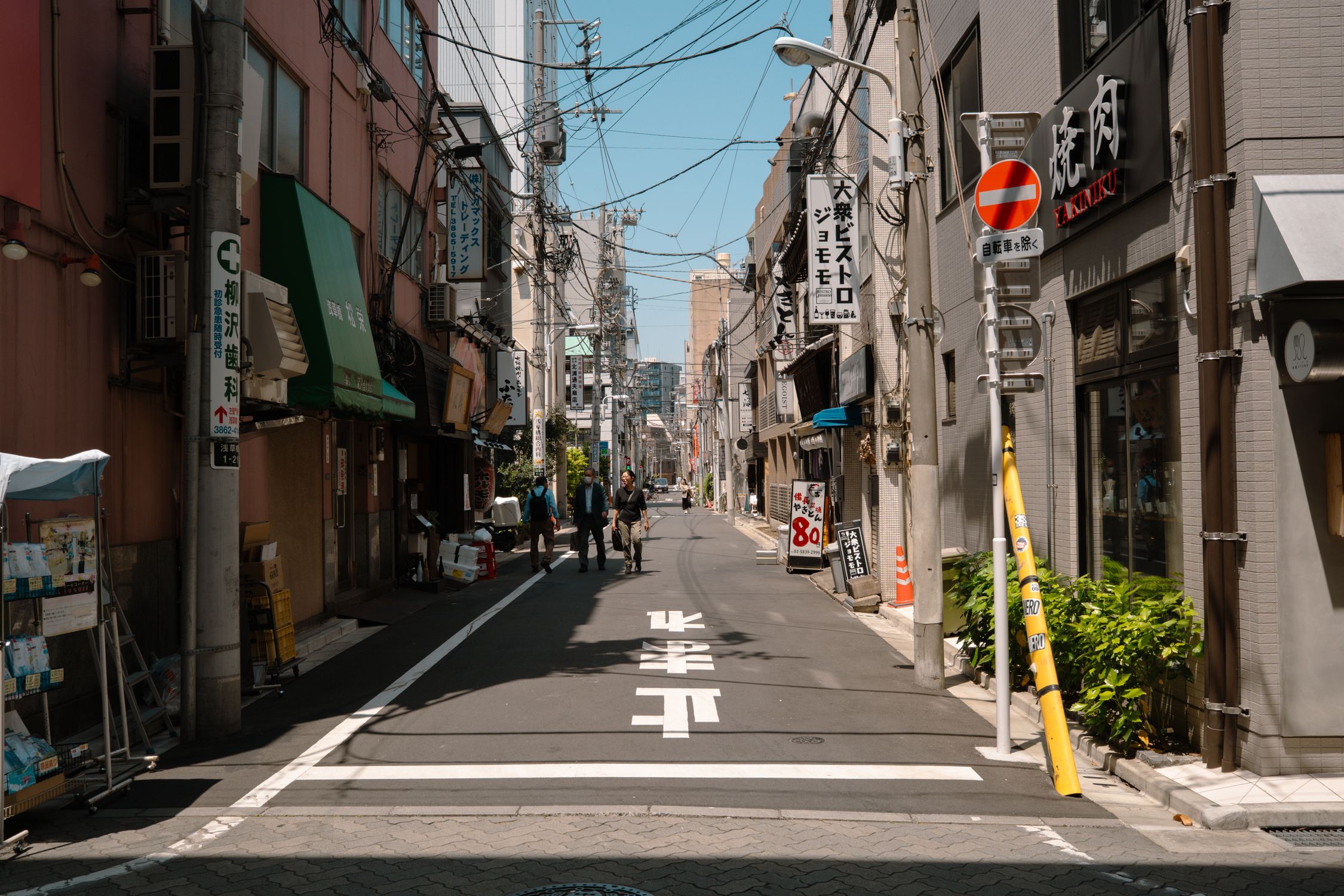A quiet street in Tokyo, showcasing urban life and traditional architecture on a sunny day.