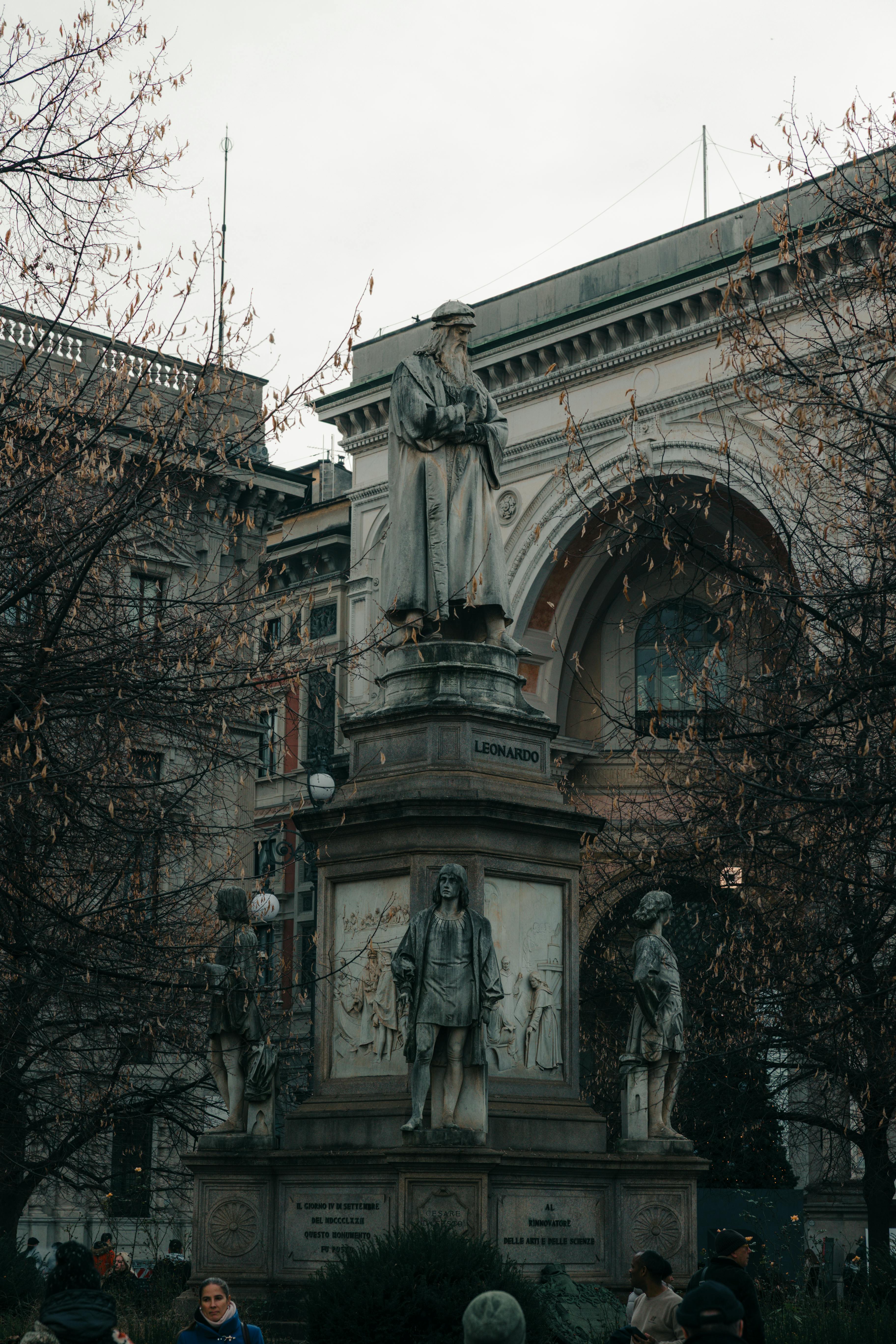 Statue of Leonardo da Vinci in Milan's Piazza della Scala with surrounding architecture.