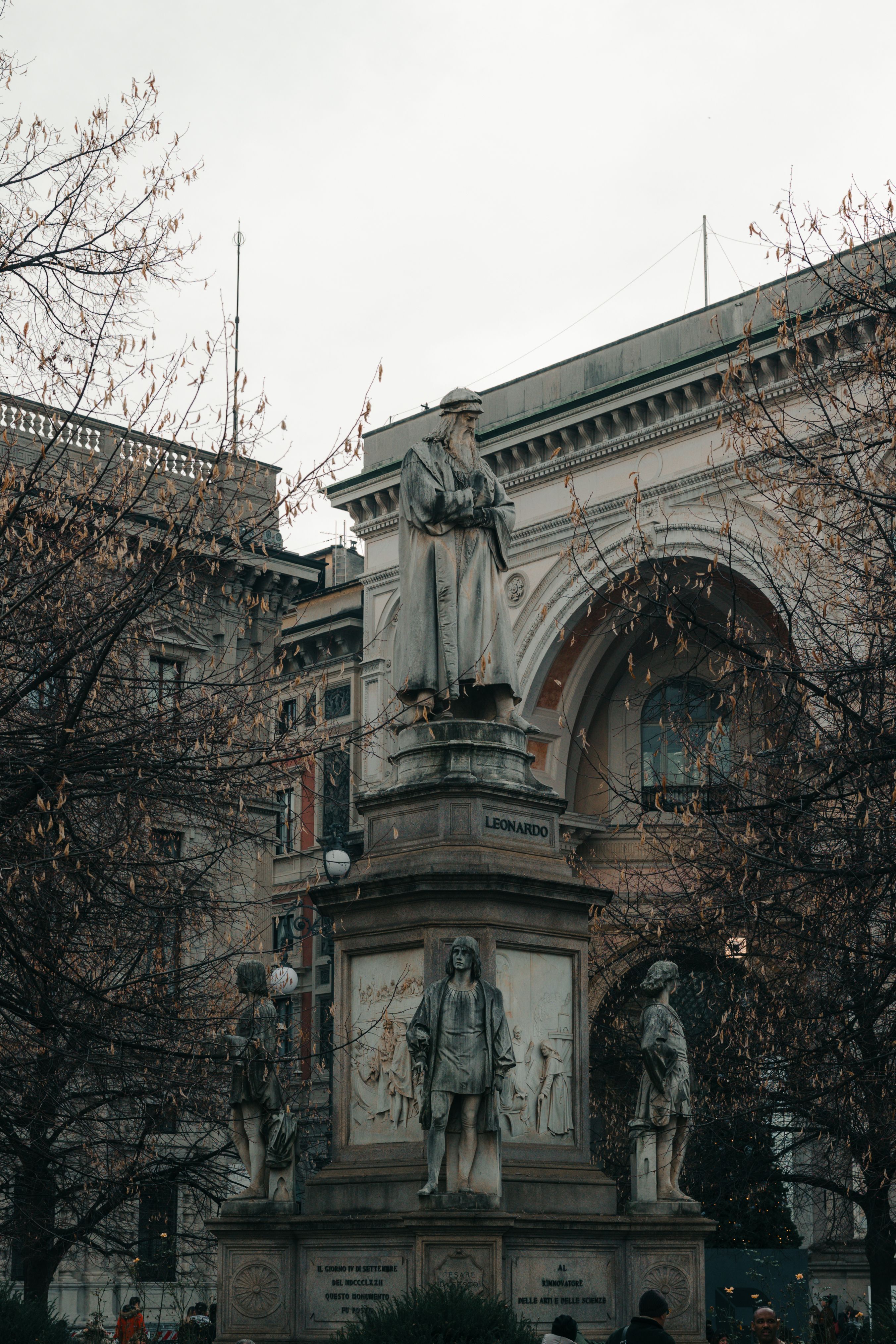 Statue of Leonardo da Vinci at Piazza della Scala, Milan, Italy, amidst autumn trees.