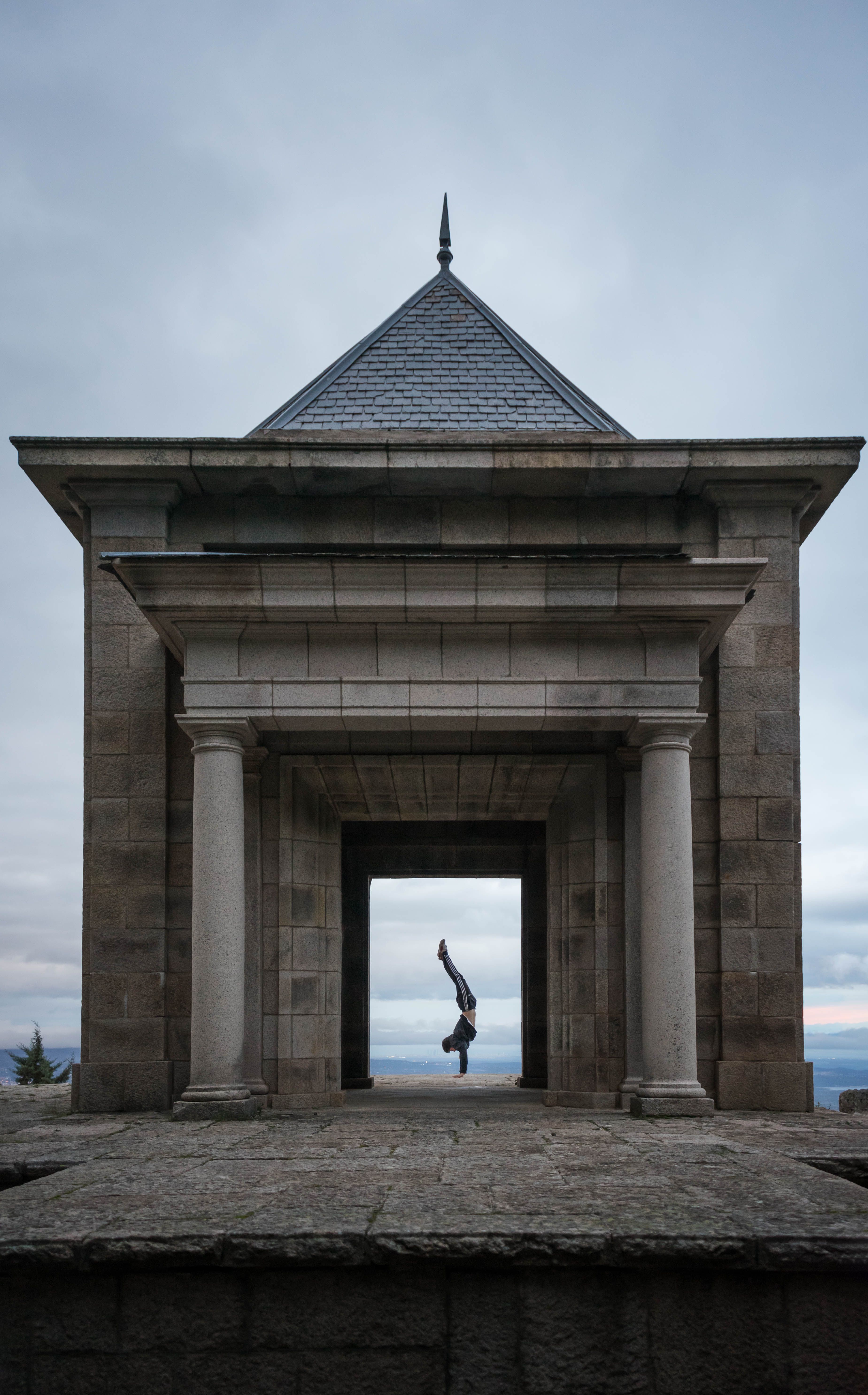 A man balances in a historic stone gazebo at twilight, showcasing balance and architecture.