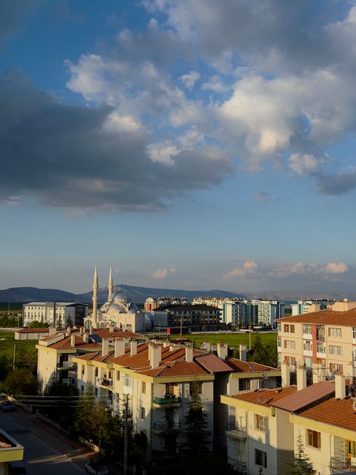 Free A serene cityscape featuring a mosque with minarets and residential buildings under a cloudy sky. Stock Photo