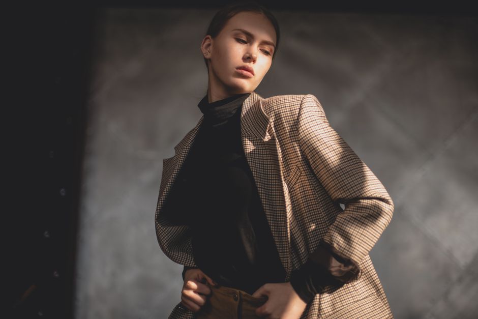 Fotomural Retrato elegante de una joven con un abrigo de cuadros, posando en interiores con luz suave.