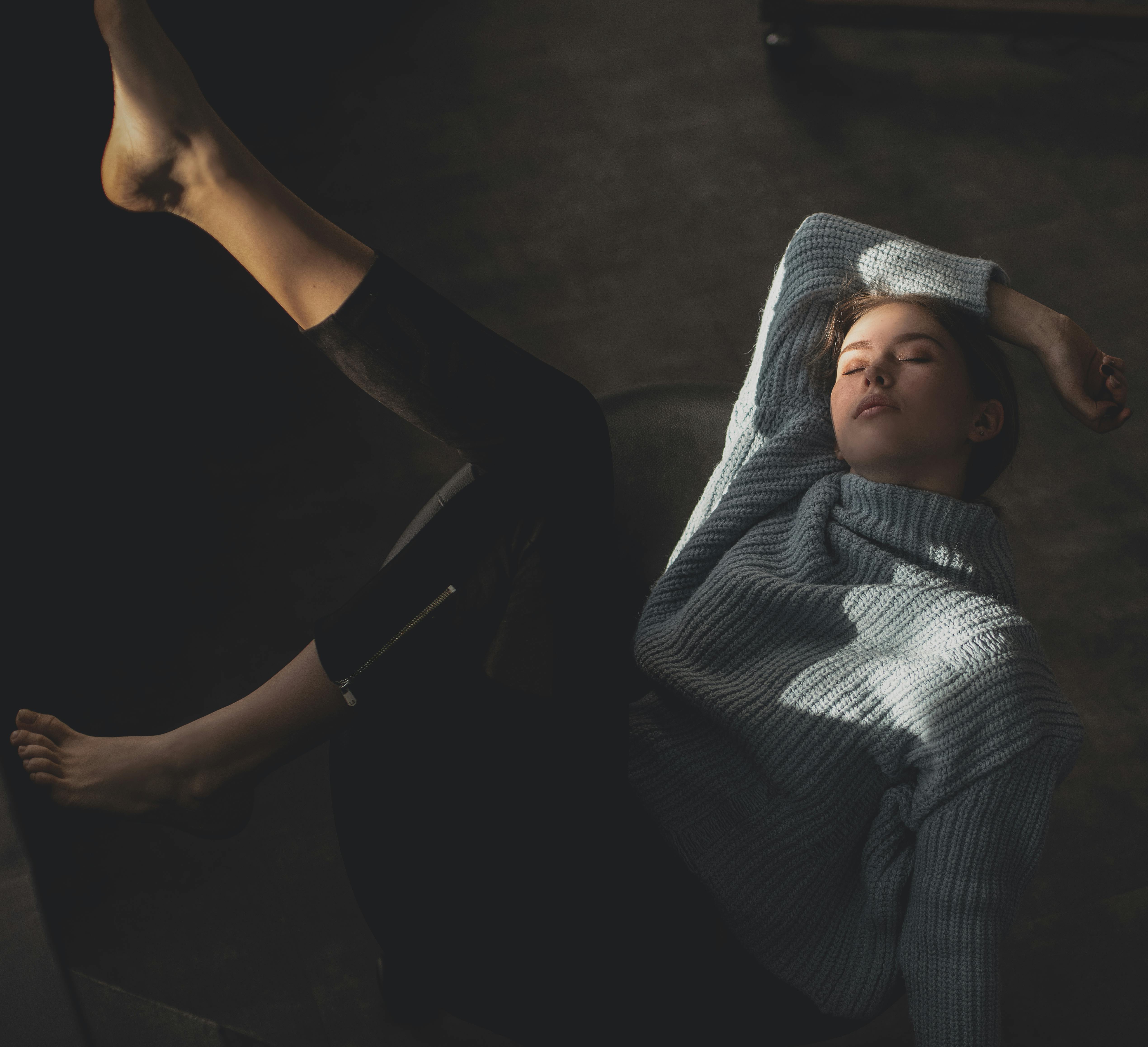 一名年轻女子穿着舒适的毛衣，在柔和的灯光下于室内放松，并被拍摄下来