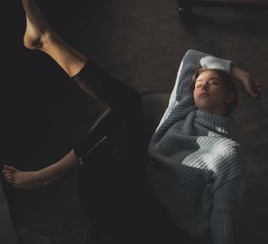 一名年轻女子穿着舒适的毛衣，在柔和的灯光下于室内放松，并被拍摄下来