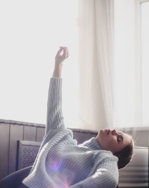 Woman in Gray Sweater Leaning Backward  Near White Window Curtain