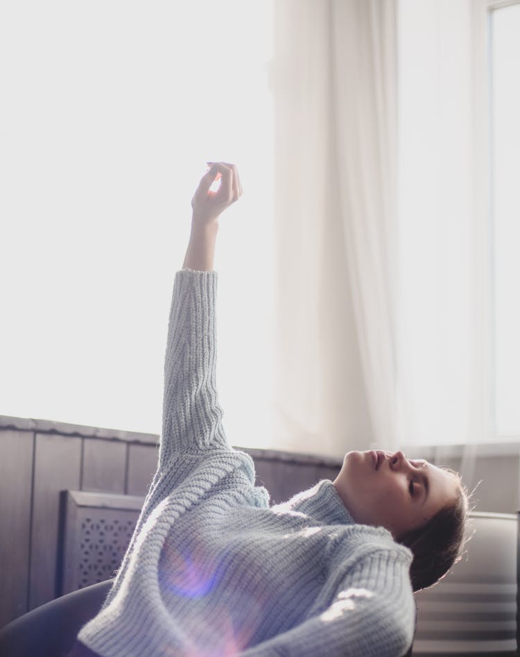 Woman In Gray Sweater Leaning Backward  Near White Window Curtain