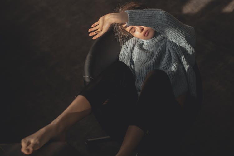 Woman In Gray Knit Sweater And Black Pants Sitting On Black Leather Chair