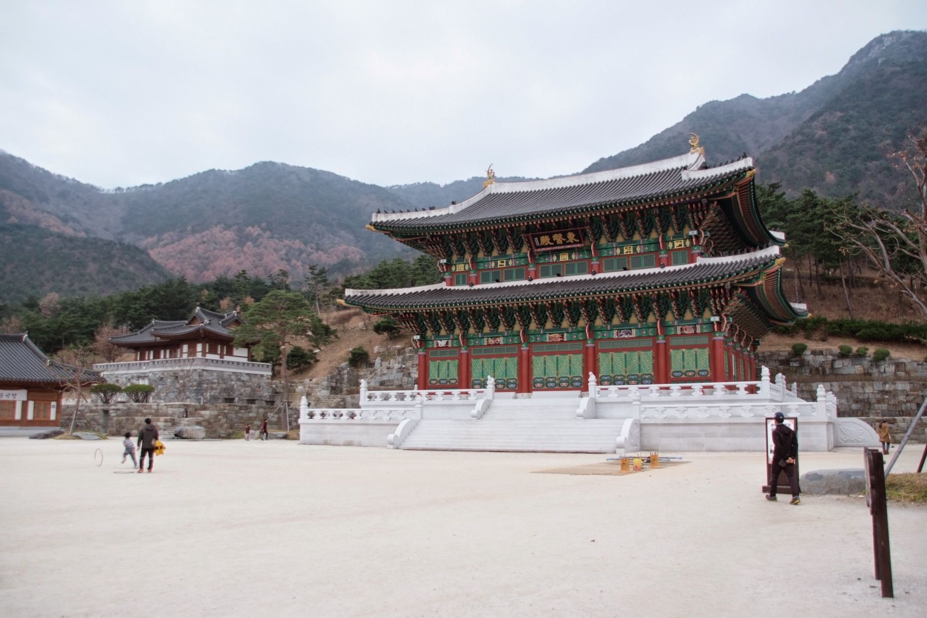A traditional Korean temple with vibrant architecture set against a picturesque mountain backdrop.