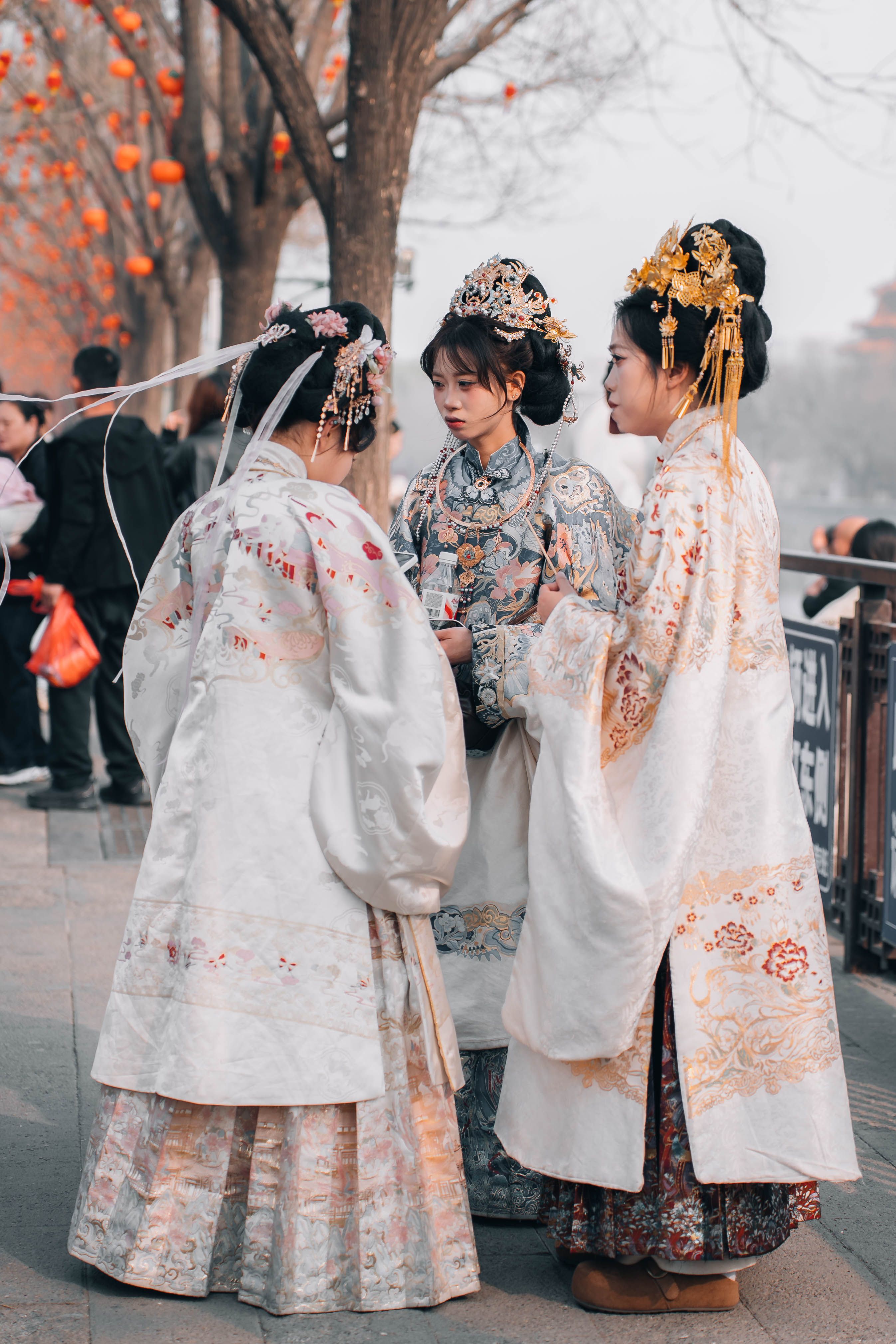 Three women in traditional Hanfu dresses at a Chinese festival, showcasing cultural heritage.