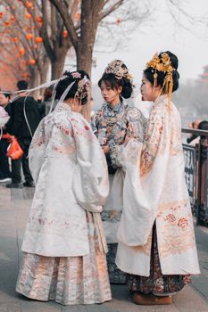 Three women in traditional Hanfu dresses at a Chinese festival, showcasing cultural heritage.