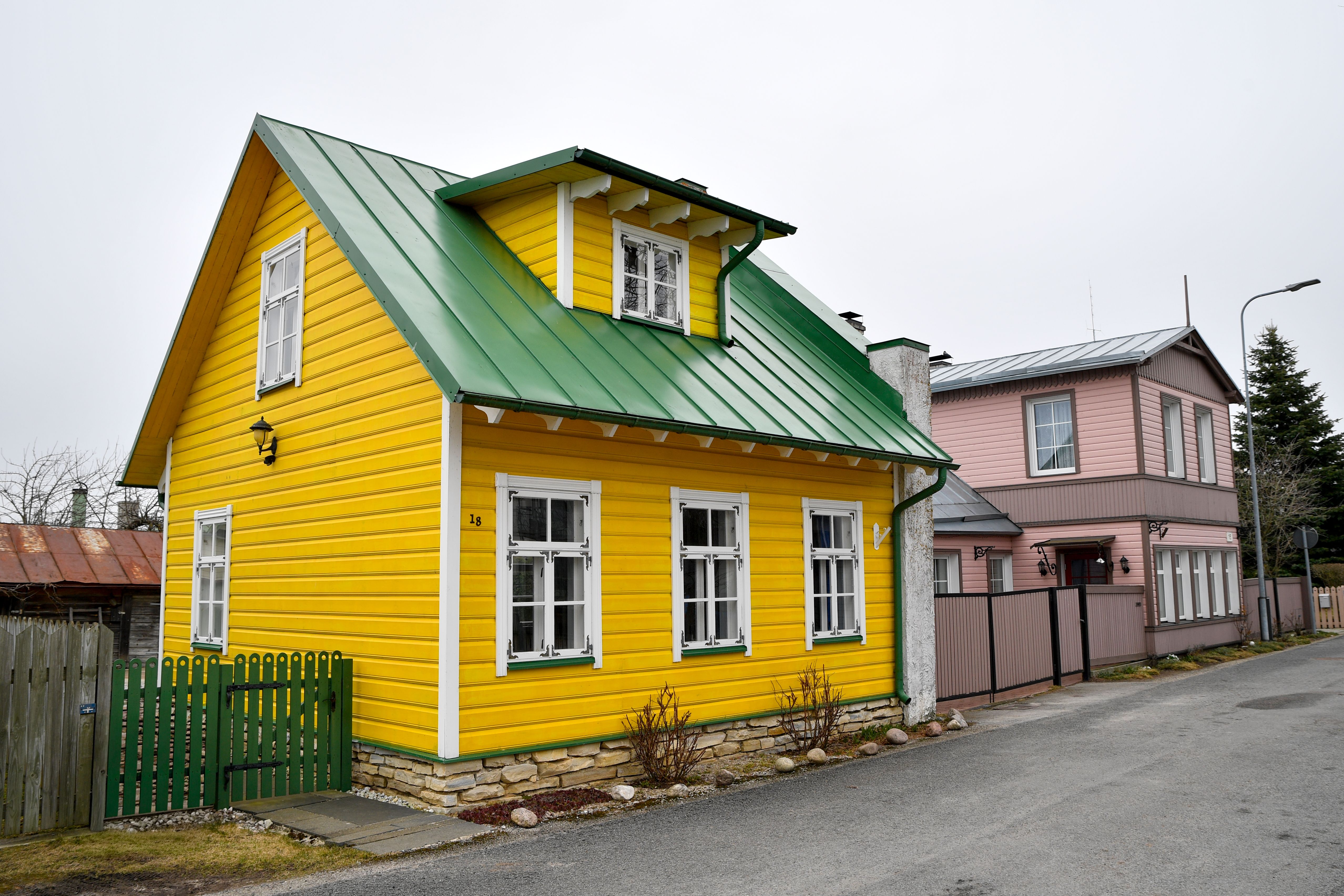 Beautiful yellow wooden house with green roof in a picturesque Estonian neighborhood.
