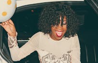 一位留着卷发的快乐年轻女子，穿着时尚的服装，享受夜晚的外出