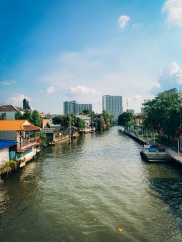 A picturesque canal scene in urban Thailand with clear blue skies and modern buildings.