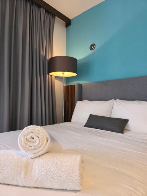 Free Inviting hotel room featuring plush bedding, rolled towels, and warm lighting. Stock Photo