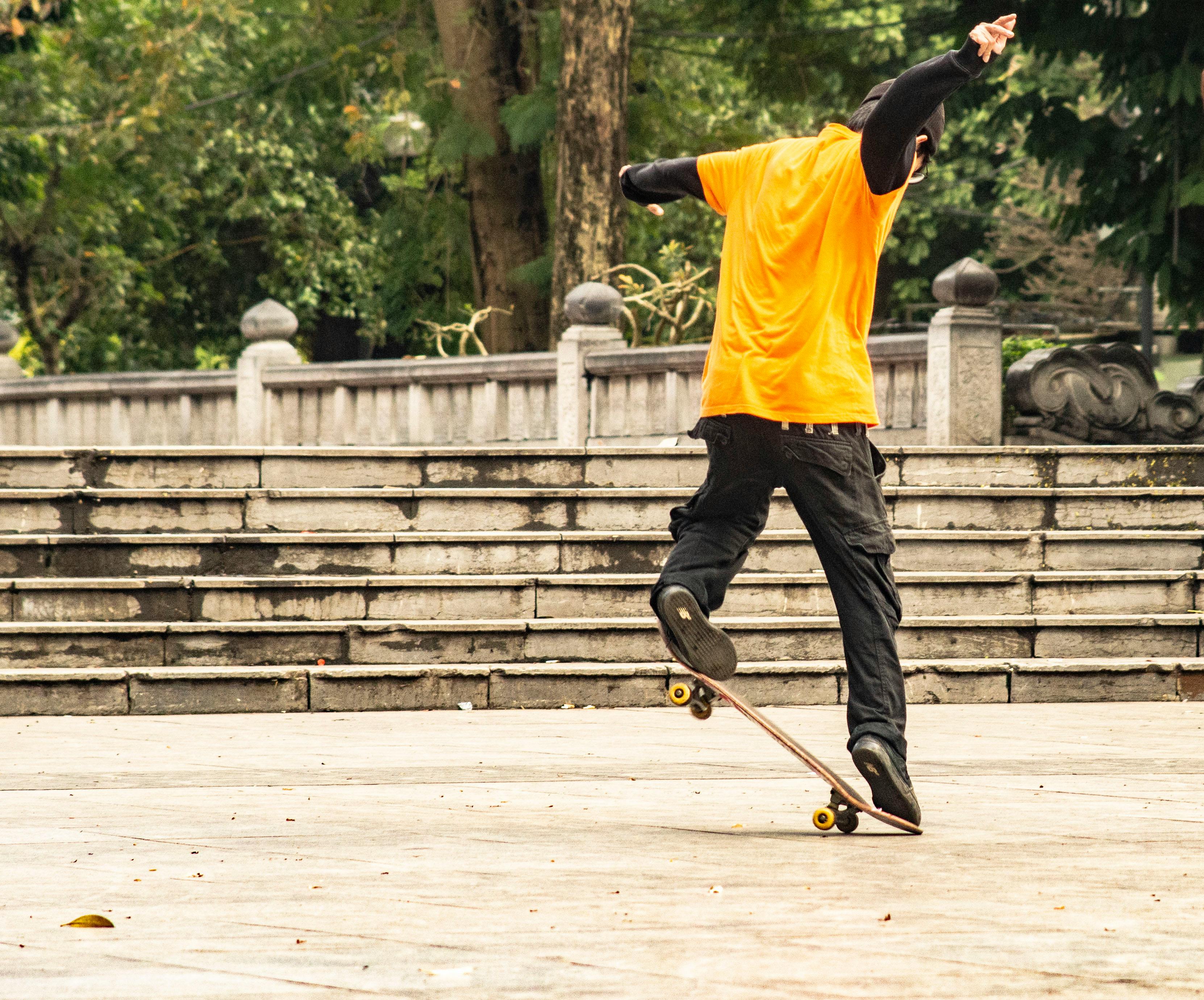 man in yellow t shirt and black pants playing skateboard