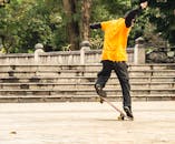 在热闹的城市公园里，一名穿着橙色衬衫的滑板手正在表演技巧