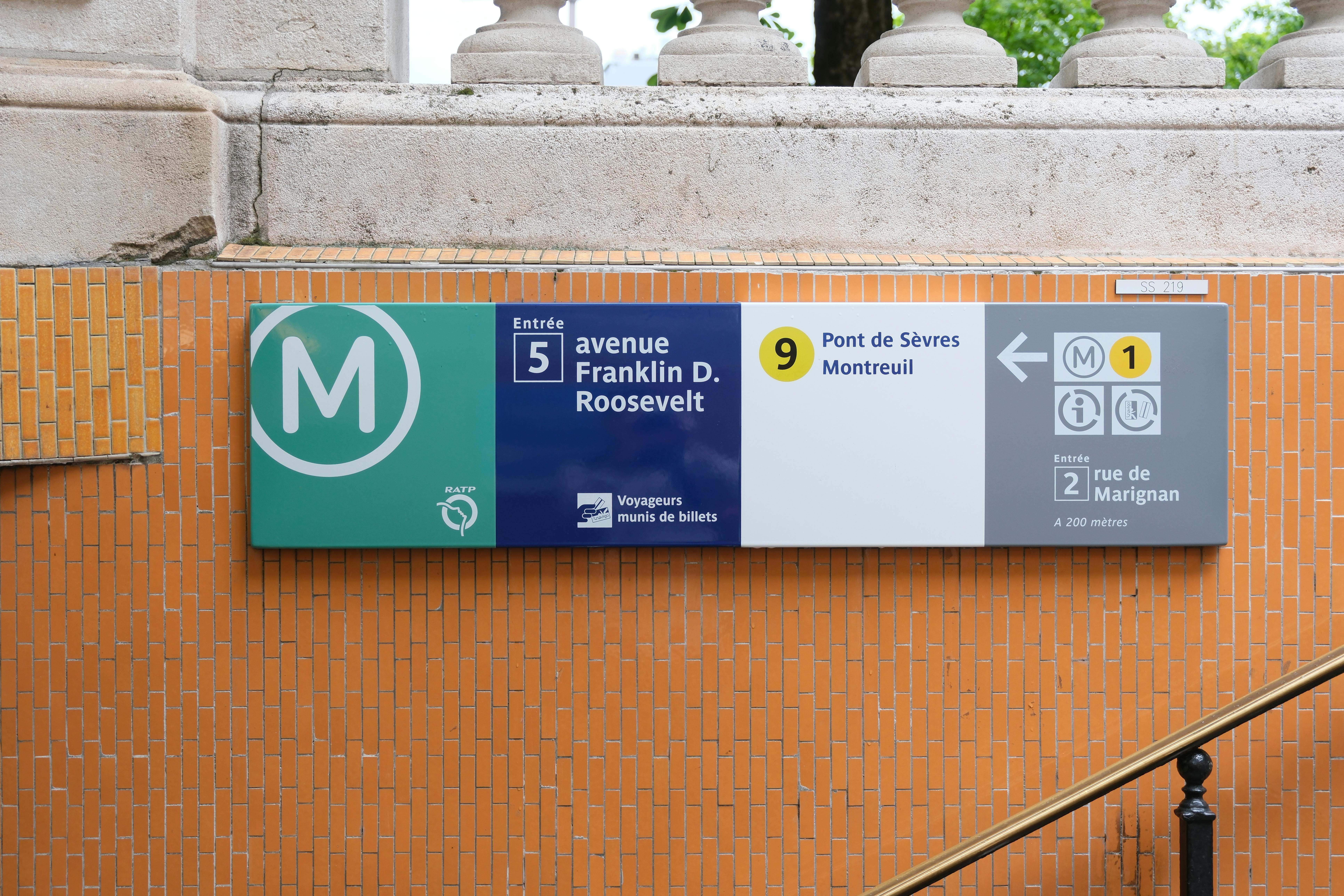 Close-up of a Paris Metro sign at Avenue Franklin D. Roosevelt entrance, featuring directions and route information.