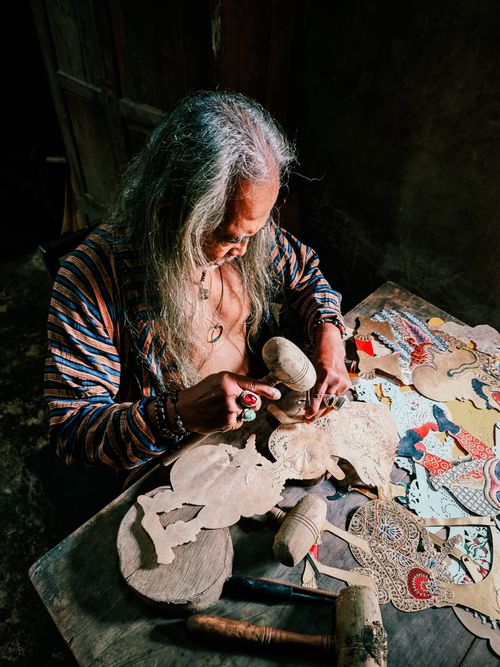 Free An artisan meticulously crafting traditional shadow puppets, showcasing detailed craftsmanship indoors. Stock Photo