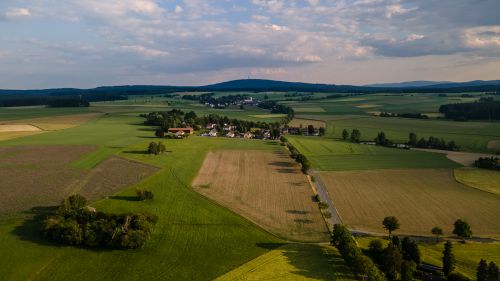 Free Aerial shot of a picturesque rural landscape in Rehau, Germany, showcasing lush fields and a small village. Stock Photo