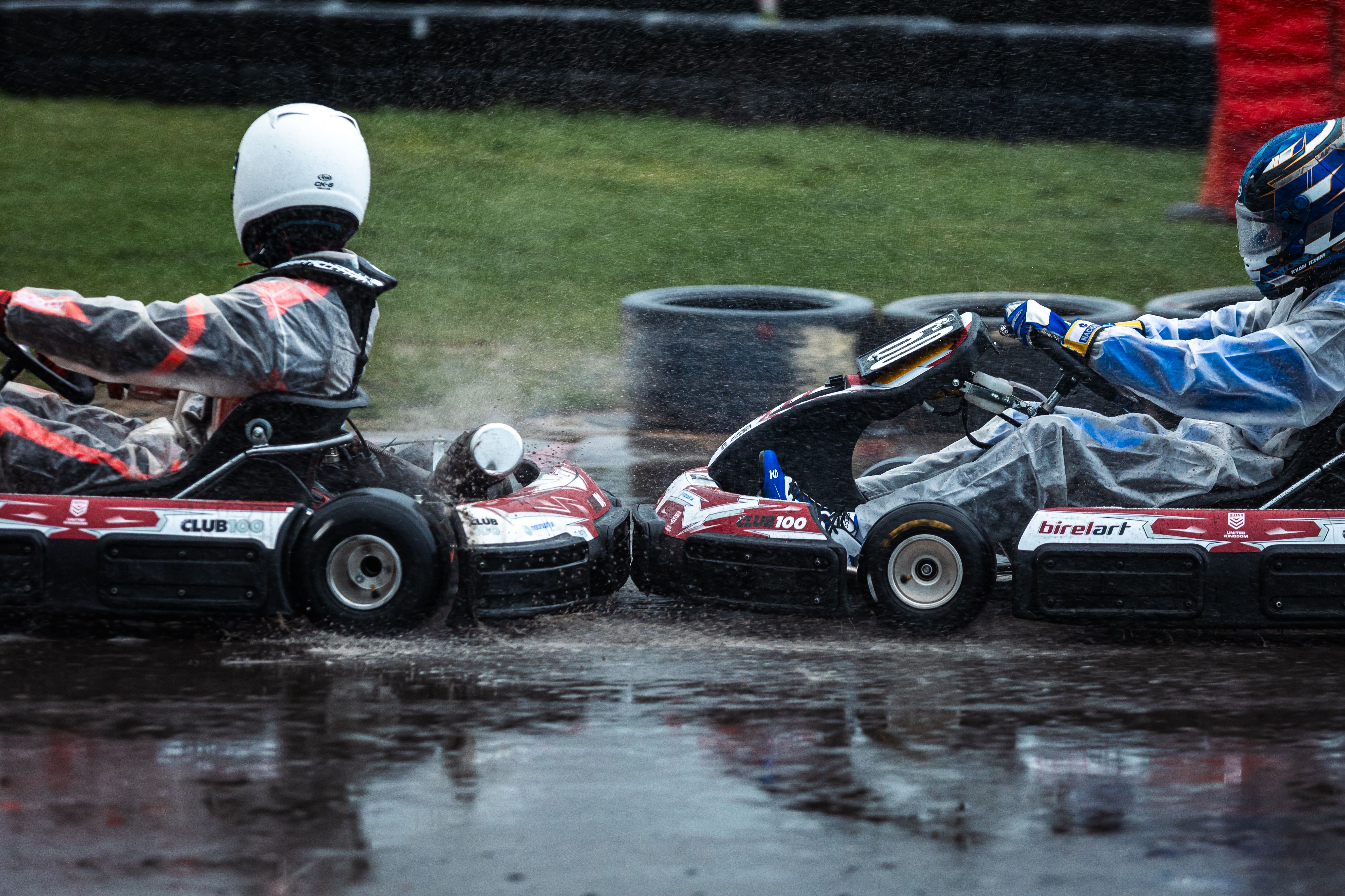 Action-packed go-kart race with drivers in rain gear competing on a wet track.