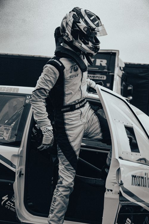 Free Race car driver stepping out of vehicle, wearing full racing gear. Stock Photo