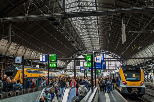Free Crowded scene at Amsterdam train station with bustling commuters and trains. Stock Photo
