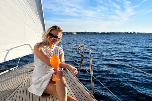 Woman enjoying a drink on a yacht in Estonia during summer, exuding elegance and leisure.