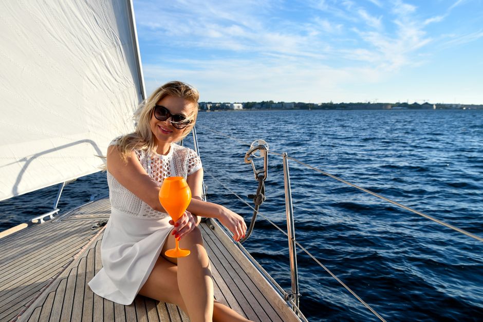 Woman enjoying a drink on a yacht in Estonia during summer, exuding elegance and leisure.