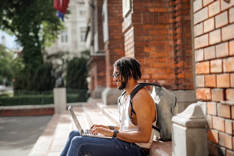 Man In White Tank Top Sitting On White Concrete Steps