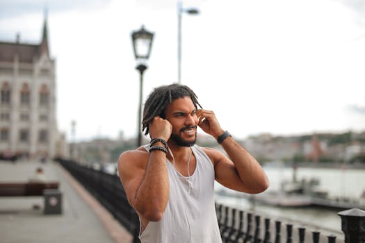 戴着耳机的年轻人在城市河边微笑，享受着户外音乐